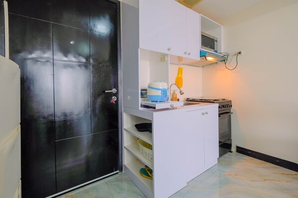 Une cuisine de taille réduite, équipée d’une cuisinière, d’un évier et de placards de rangement.
