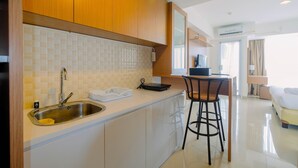 Una cucina moderna con lavello in acciaio inossidabile, un piano di lavoro bianco e mobili in legno. È presente uno sgabello bar vicino al bancone della cucina.