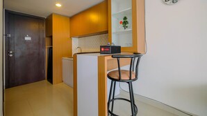 Una cucina compatta con mobili in legno, una piccola isola, uno sgabello da bar e una sveglia appesa al muro.
