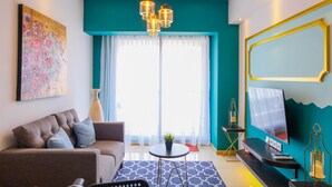 A modern living room with a sofa, a coffee table, a TV, and a large window with curtains. - Elegant 2BR Apartment at M-Town Signature near Shopping Mall (Gading Serpong)