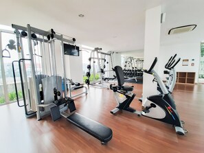 Ein modernes Fitnessstudio mit verschiedenen Trainingsgeräten, darunter Kraftgeräte, eine Hantelbank und Cardiogeräte.