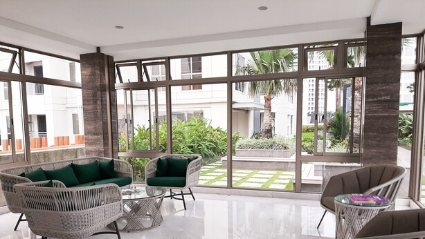 A spacious indoor area with large windows, wicker furniture, and a tiled floor. - Elegant 2BR Apartment at M-Town Signature near Shopping Mall (Gading Serpong)