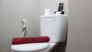 A white toilet with a red towel on the seat and a water bottle on top. - Classic Studio Room Taman Melati Apartment Jatinangor near UNPAD (Hegarmanah)