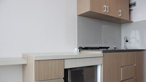 A modern kitchen with wooden cabinets, a built-in dishwasher, and a stainless steel sink. - Classic Studio Room Taman Melati Apartment Jatinangor near UNPAD (Hegarmanah)
