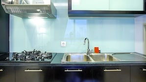 A modern kitchen with a stainless steel range hood, a double sink, and black cabinetry. - Stunning 2BR at The Empyreal Condominium Epicentrum Apartment (Jakarta)