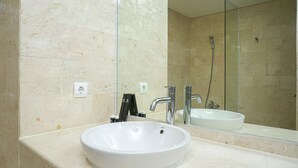 A bathroom with a white sink, a mirror, and a shower. - Stunning 2BR at The Empyreal Condominium Epicentrum Apartment (Jakarta)
