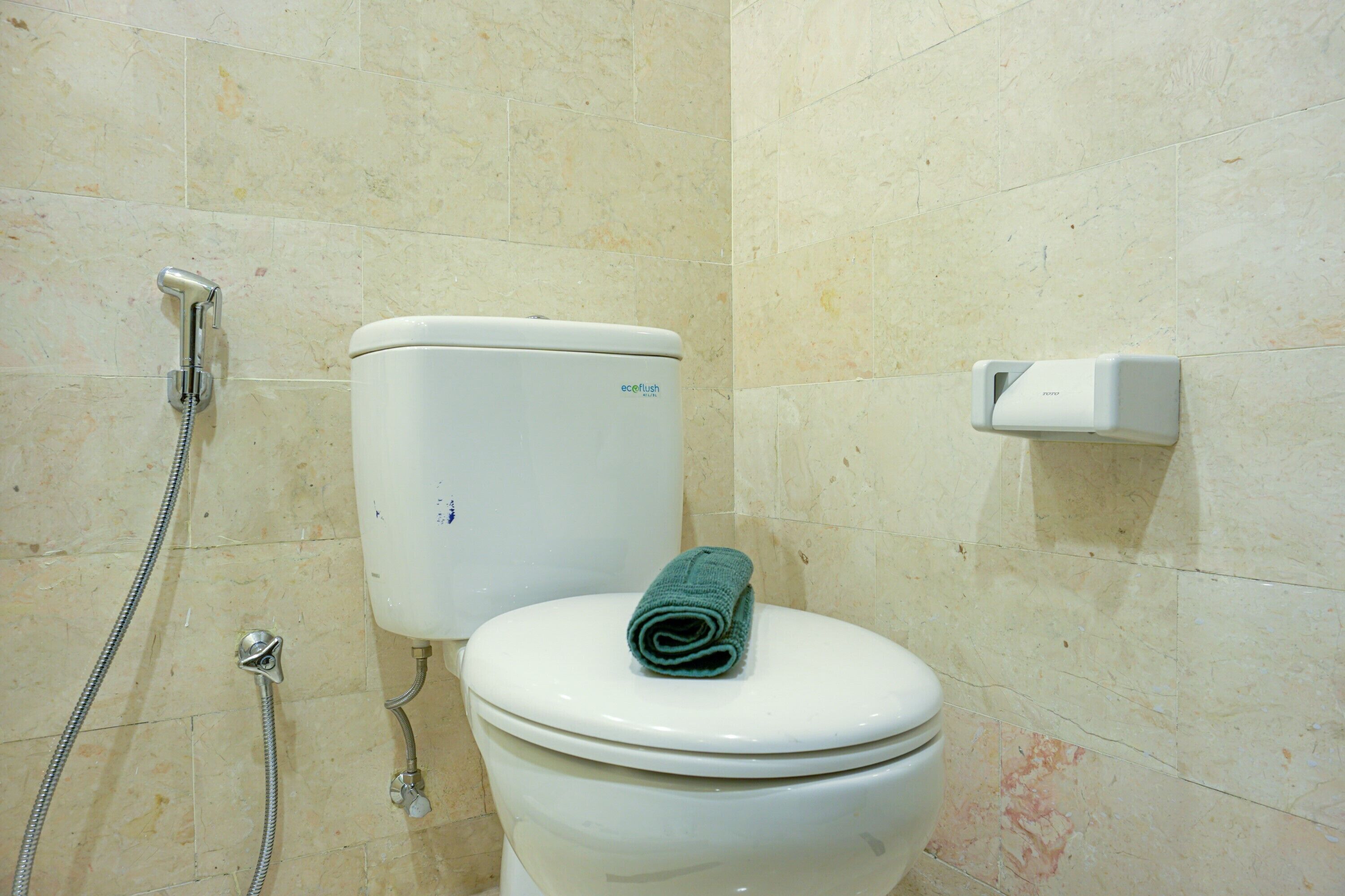 A bathroom with a toilet, a shower, and a soap dispenser.