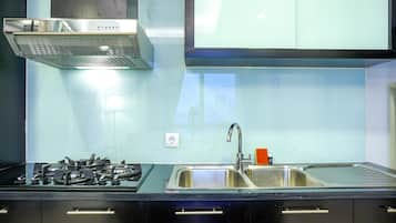 A modern kitchen with a stainless steel range hood, a double sink, and black cabinetry.