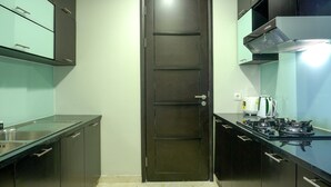 A modern kitchen with a dark door, stainless steel appliances, and light green cabinets. - Cozy 2BR @ The Empyreal Condominium Epicentrum Apartment (Jakarta)