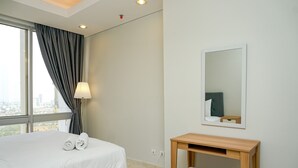 A hotel room with a bed, a bedside table, a mirror, and a view of the city through a large window. - Cozy 2BR @ The Empyreal Condominium Epicentrum Apartment (Jakarta)