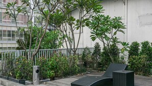 A rooftop garden with a lounge chair and a trash bin. - Luxury 2BR at The Empyreal Condominium Epicentrum Apartment (Jakarta)
