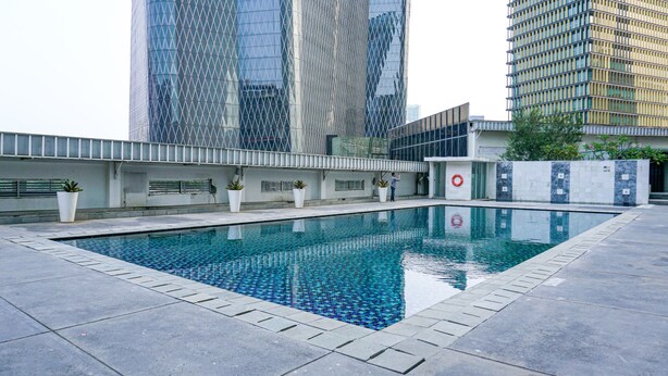 A swimming pool with a tiled edge, surrounded by a low wall and potted plants. - Luxury 2BR at The Empyreal Condominium Epicentrum Apartment (Jakarta)