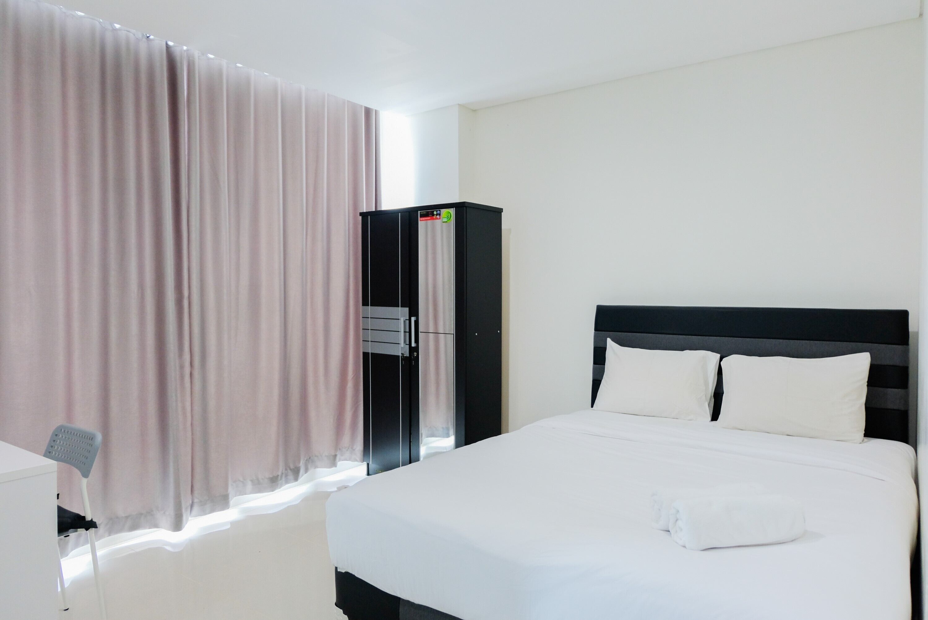 A hotel room with a bed, a wardrobe, and a desk.