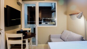 Een compact woongedeelte met een flatscreen televisie aan de wand, een eettafel met stoelen, een bank en een raam met uitzicht.