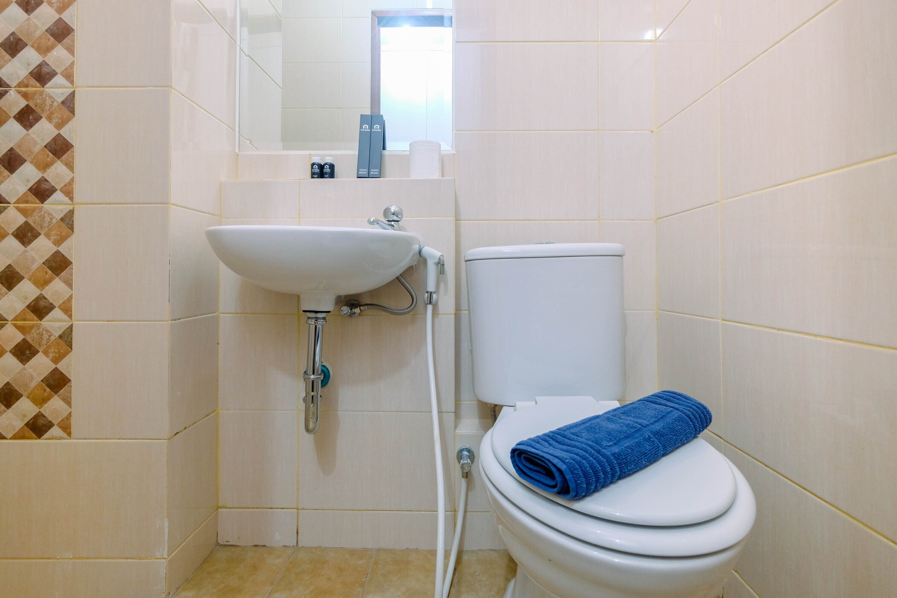 Une salle de bain avec un lavabo blanc, des toilettes et une serviette bleue posée sur les toilettes.