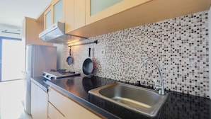 A modern kitchen with a black countertop, stainless steel sink, and a tiled backsplash. - Cozy Studio at Tamansari Semanggi Apartment (Jakarta)