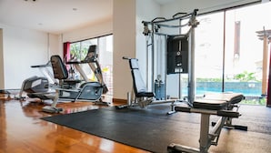 A gym with cardio machines, weight training equipment, and a large window with a view of the outdoors. - Cozy Studio at Tamansari Semanggi Apartment (Jakarta)