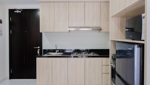 A modern kitchen with light wood cabinets, a stainless steel stove, and a built-in oven. - Elegant 1BR Apartment at Casa De Parco near AEON Mall (Pagedangan)