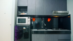 Una cucina moderna con un forno a microonde, un piano cottura a gas e tazze arancioni sul bancone.
