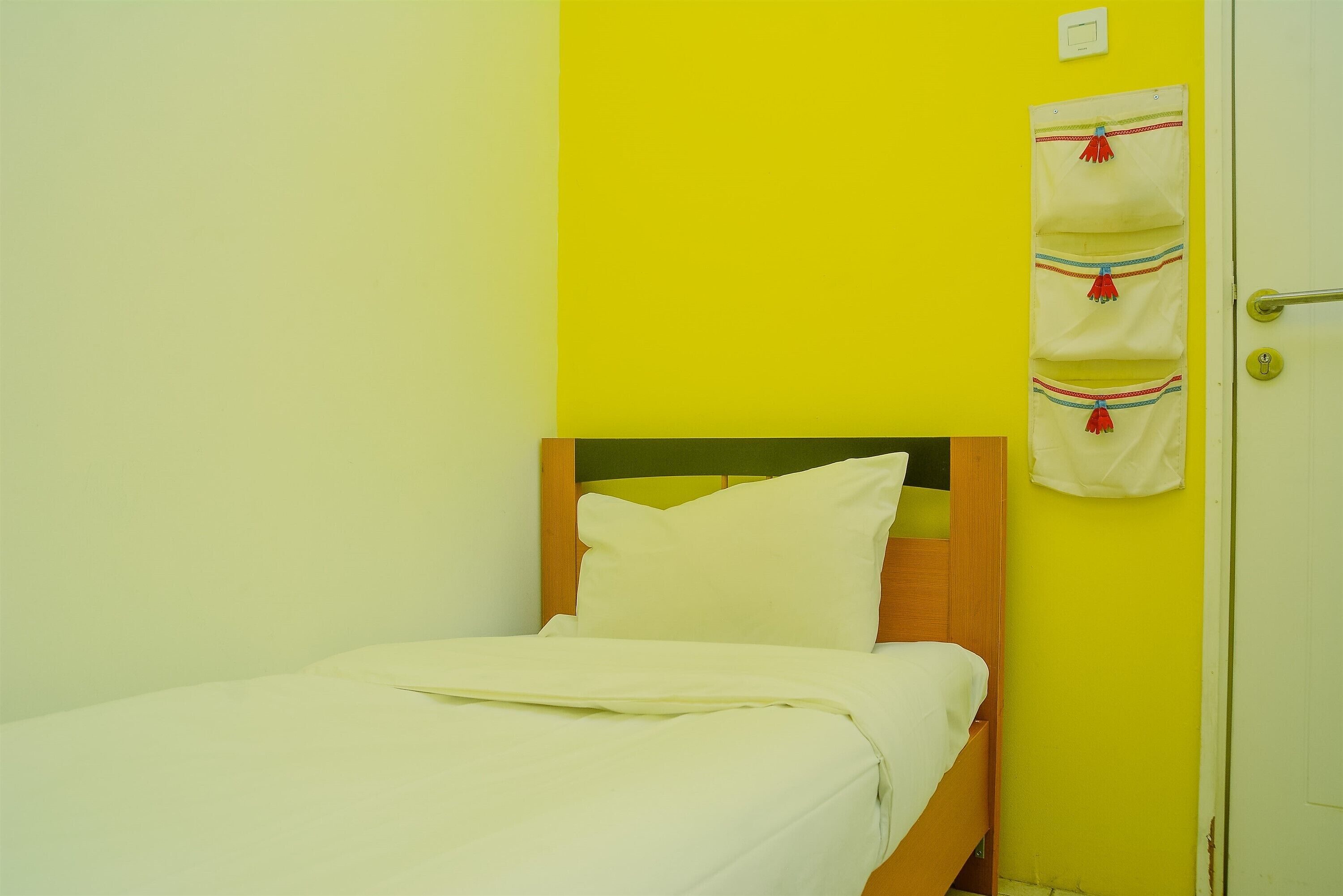 A single bed with a wooden headboard in a room with yellow walls.