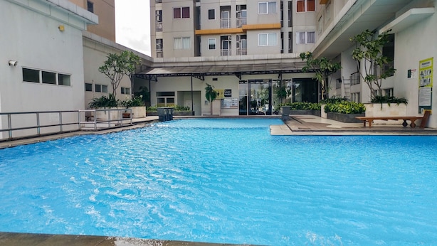 Una piscina con zona coperta e una panchina, circondata da edifici.