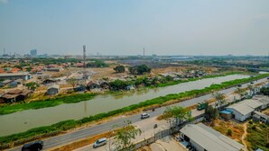 A river running alongside a road with buildings and greenery. - Affordable Price Studio at Jababeka Riverview Apartment Cikarang (Cikarang)