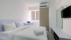 A hotel room with a bed, a TV, a desk, and a window. - Affordable Price Studio at Jababeka Riverview Apartment Cikarang (Cikarang)