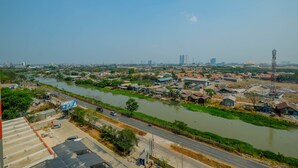 A river flowing through a town with buildings and a road alongside. - Affordable Price Studio at Jababeka Riverview Apartment Cikarang (Cikarang)