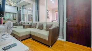 Een moderne woonkamer met een hoekbank, een witte ventilator en een afstandsbediening op een tafel.