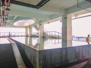 An indoor swimming pool with a central staircase, surrounded by columns and railings. - 1BR Apartment Atlanta Residences next to RS Bunda Margonda (Depok)