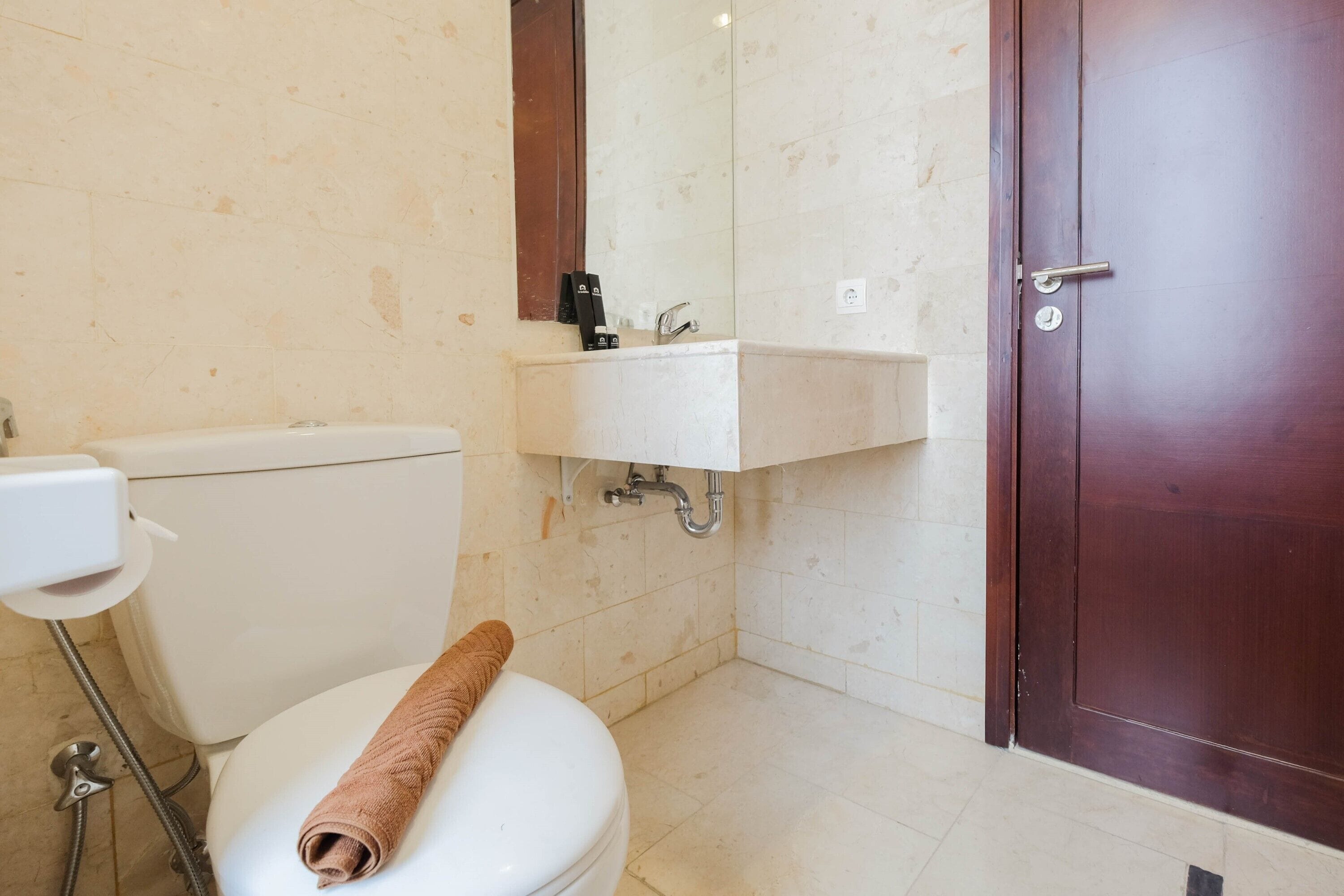 Un baño con inodoro, lavabo y puerta de madera.