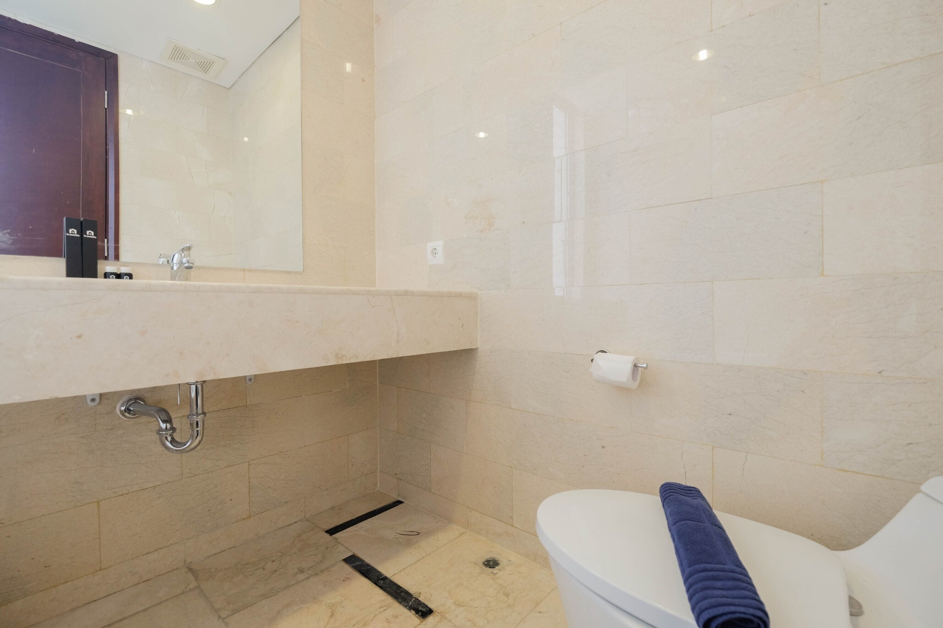 Un baño con lavamanos de mármol, inodoro y zona de ducha.