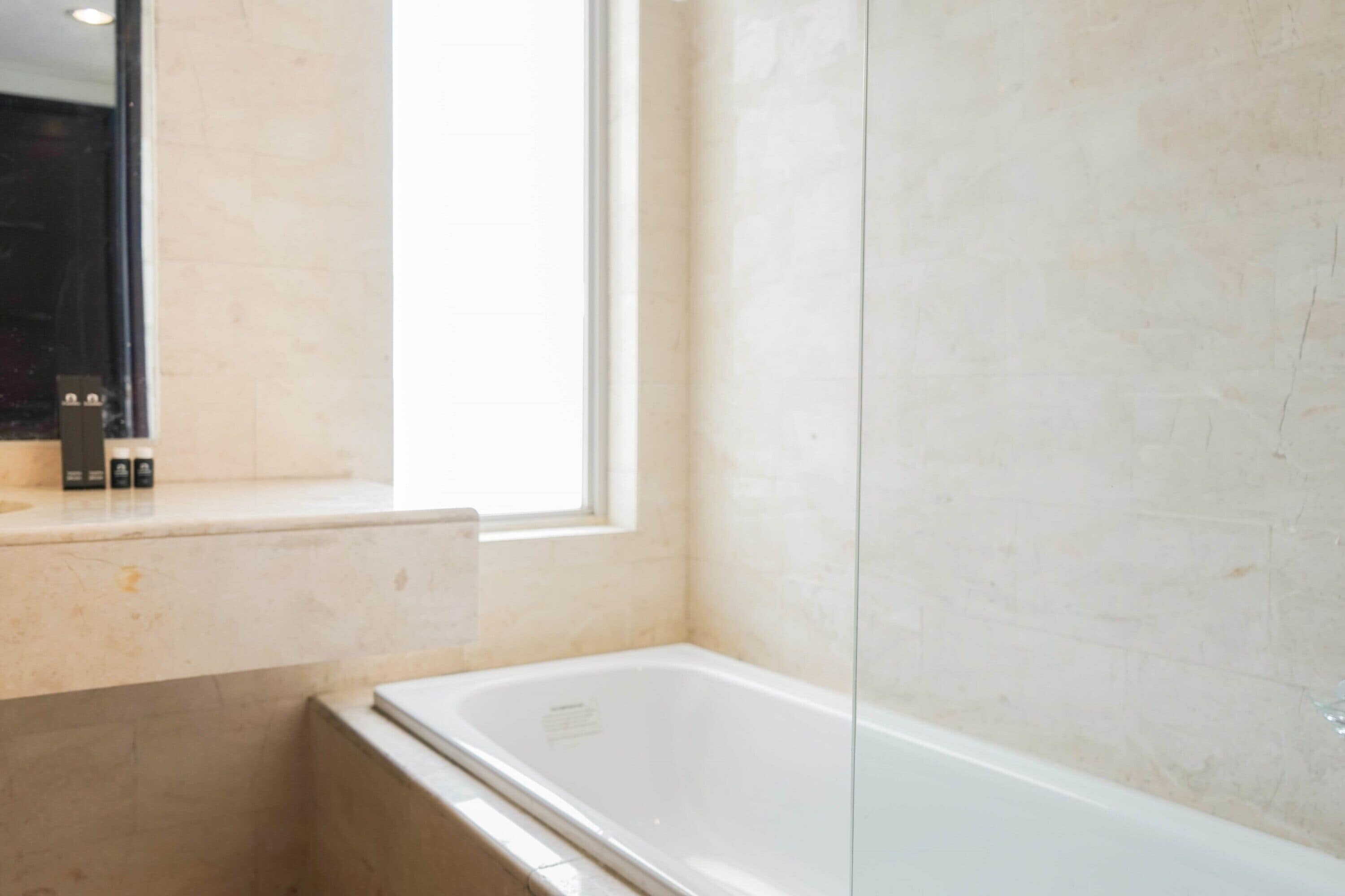 Une salle de bain moderne avec une baignoire, une fenêtre et un miroir.