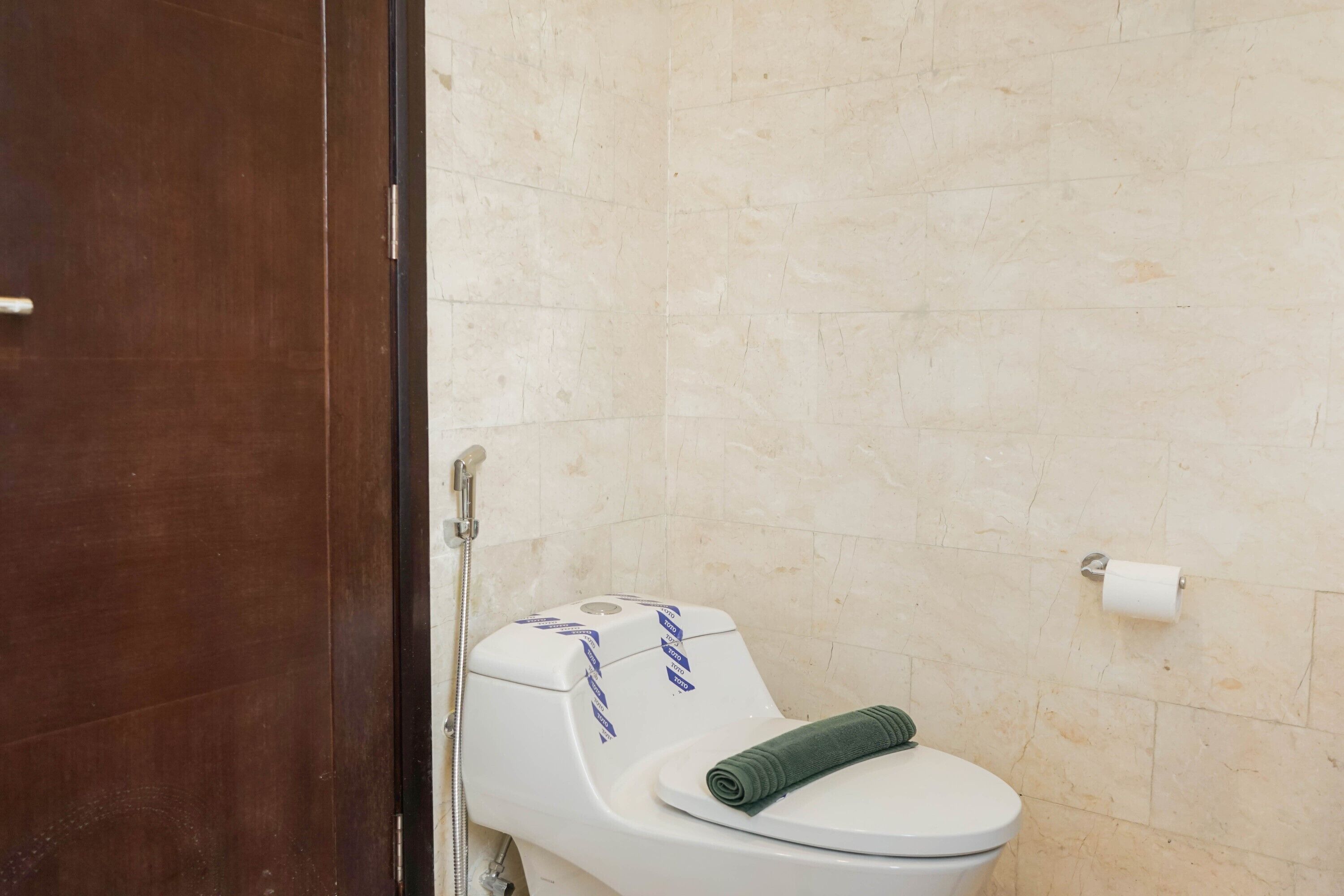 Kylpyhuone, jossa on wc, pyyhe ja seinällä wc-paperirulla.