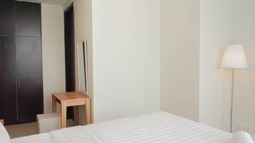A hotel room with a bed, a desk, a wardrobe, and a lamp.