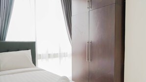 A neatly made bed with a rolled white towel, a dark headboard, and a wardrobe with silver handles. - Exclusive 2BR @ The Empyreal Condominium Epicentrum Apartment (Jakarta)