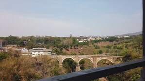 A stone bridge with multiple arches spanning a river, surrounded by greenery and buildings in the background. - Cozy Studio near UNPAD at Taman Melati Apartment Jatinangor (Hegarmanah)