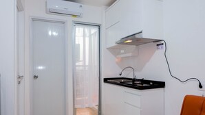 A compact kitchen with white cabinets, a black countertop, and a stainless steel sink. - Pleasant 2BR Apartment at Bassura City near Shopping Mall (Jakarta)