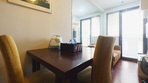 A hotel room with a dining table, chairs, a water dispenser, and a large window with blinds. - Best Choice 1BR Apartment at Kebagusan City (Jakarta)