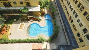 An aerial view of a residential building with a swimming pool, solar panels, and a gated entrance. - Best Choice 1BR Apartment at Kebagusan City (Jakarta)