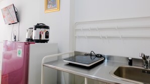 A kitchenette with a microwave, a rice cooker, a pink water dispenser, and a sink. - Comfortable and Fully Furnished Studio at Poris 88 Apartment (Tangerang)