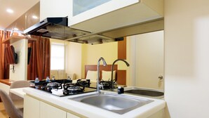 A compact kitchen with a gas stove, two sinks, and a window with curtains. - Highest Value Studio Apartment at Parkland Avenue (South Tangerang)