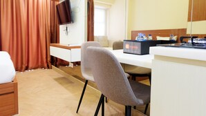 A hotel room with a bed, a desk, a chair, a television, and a minibar. - Highest Value Studio Apartment at Parkland Avenue (South Tangerang)