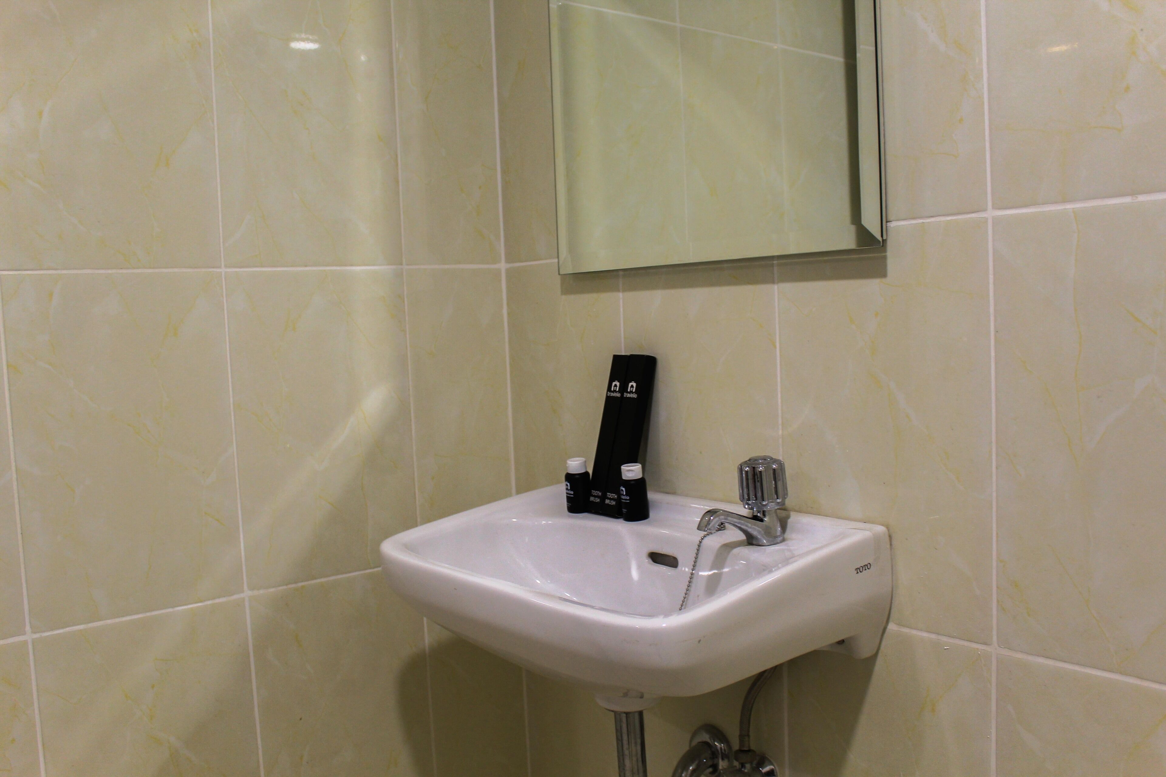 Une salle de bain avec un lavabo blanc, un miroir et un distributeur de savon.