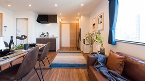 Uma sala de estar moderna com área de jantar, sofá, televisão e janela com cortinas.