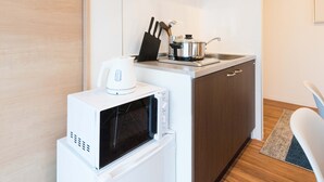 Une cuisine compacte équipée d’un four à micro-ondes, d’une cuisinière et d’une hotte noire.