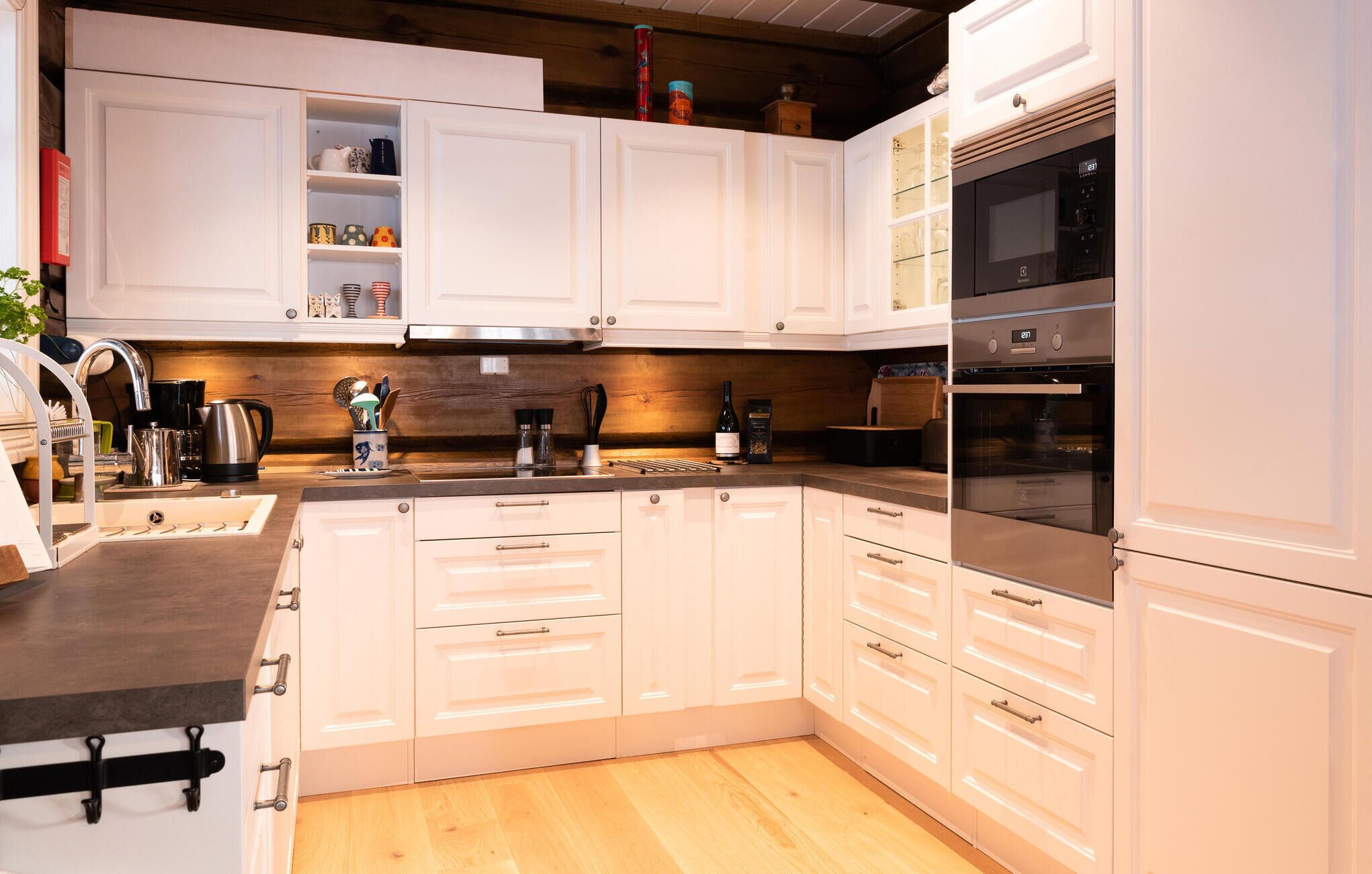 A modern kitchen with white cabinetry, stainless steel appliances, and a wooden countertop.