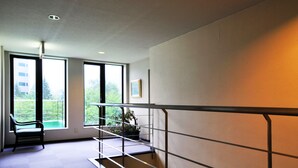 A modern interior with a staircase, large windows, a bench, and a potted plant. - Pension Shadow Classe (Otaru)