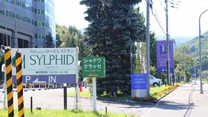 A road sign for SYLPHID restaurant with operating hours and a nearby green sign for Pension Shadow Class. - Pension Shadow Classe (Otaru)