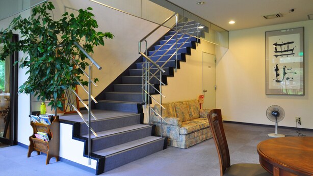 A modern interior with a staircase, a sofa, a dining table, and a fan. - Pension Shadow Classe (Otaru)